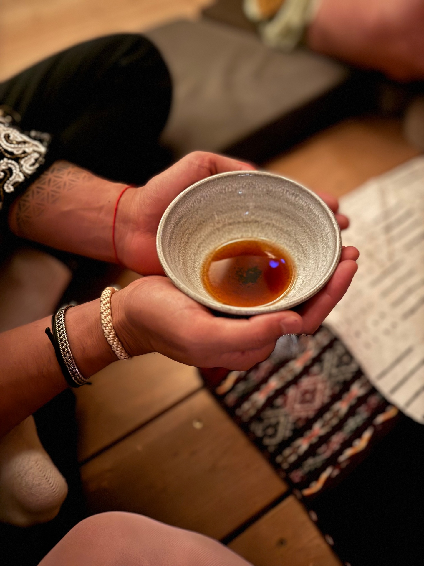 Hands cradling a ceremonial bowl of tea