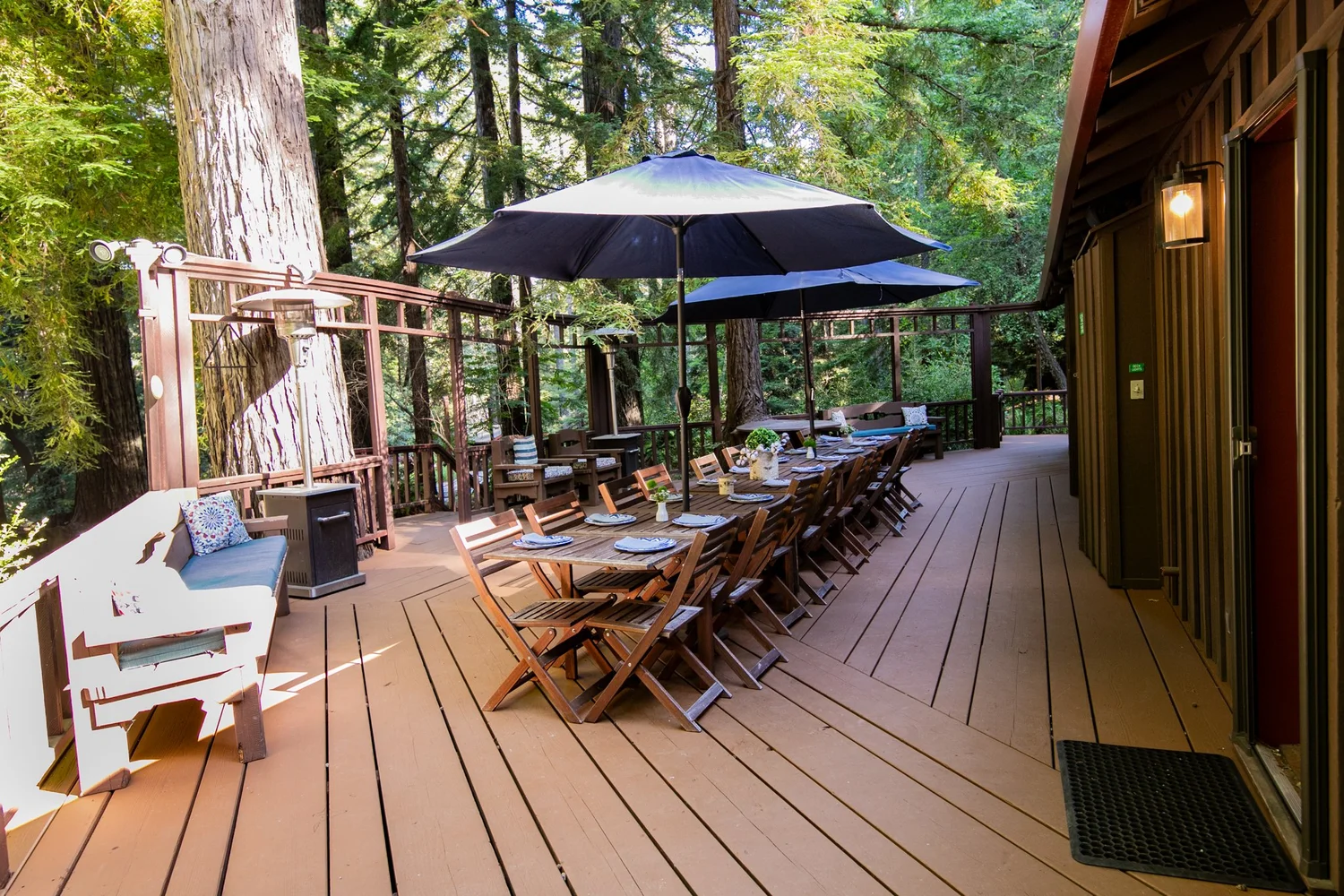 Long communal dining table on a redwood deck under the trees